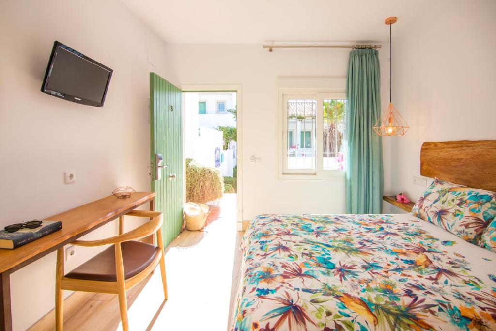 a bedroom with a bed and a desk and a window at Fortuna in Los Caños de Meca