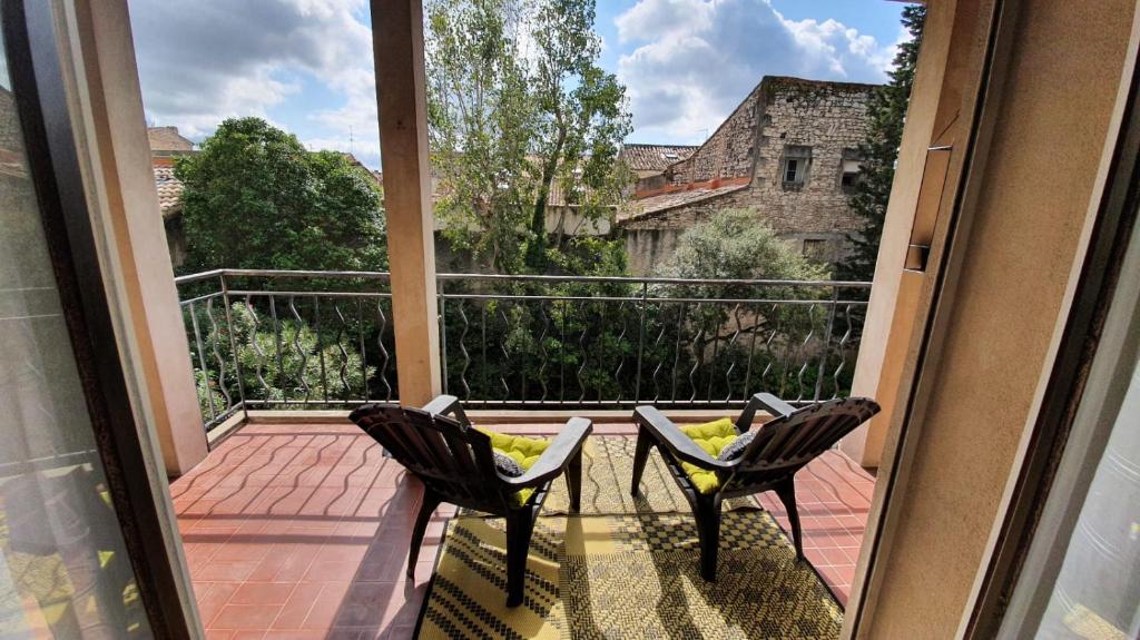 a balcony with two chairs and a large window at Lovely Suite Nimes Romaine in Nîmes