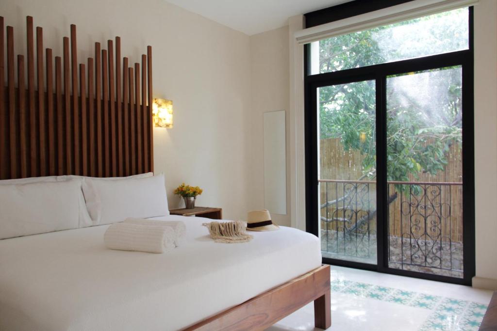 1 dormitorio con cama blanca y ventana grande en TreeHouse Boutique Hotel, an adults only boutique hotel en Mérida