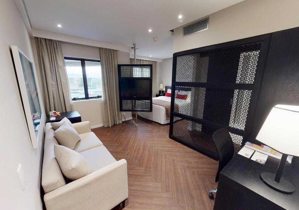 uma sala de estar com um sofá branco e uma televisão em Estanplaza Funchal Faria Lima em São Paulo