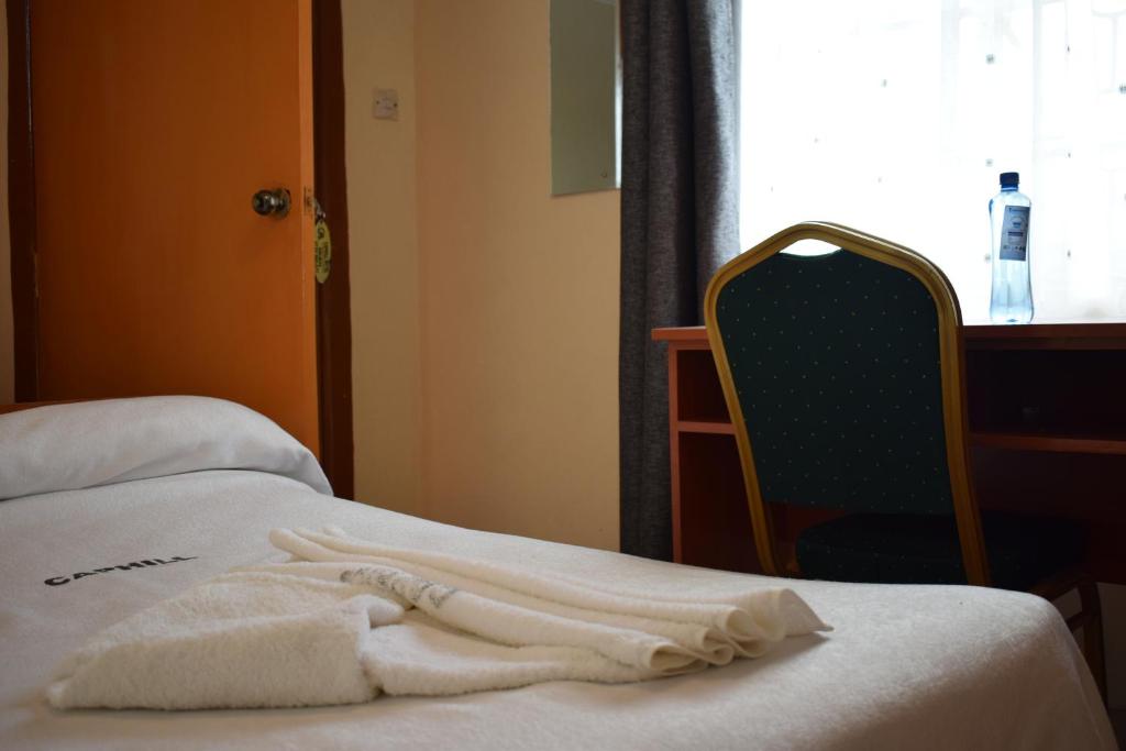 a white towel sitting on a bed next to a chair at Caphill Hotel in Syokimau