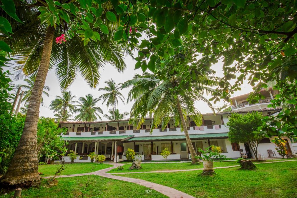 an exterior view of a resort with palm trees at Sea view Beach Resort in Unawatuna
