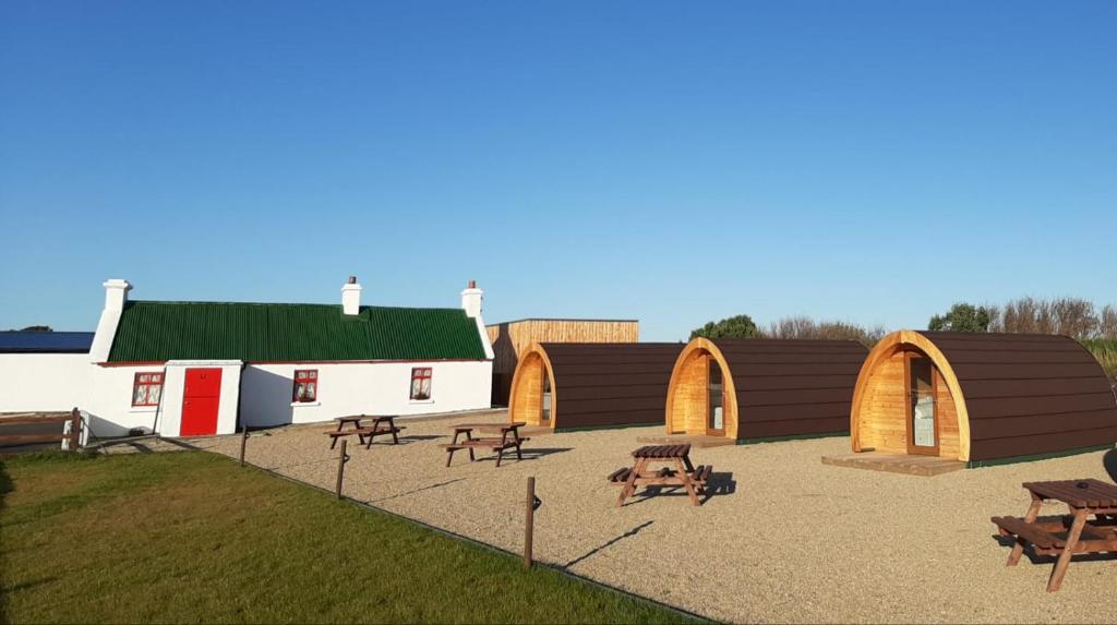 un grupo de edificios con mesas de picnic y bancos en Geraghtys Farmyard Pods, en Mayo