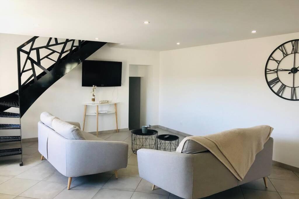 a living room with a couch and a clock on the wall at La campagne proche de Charleville-Mezieres in This