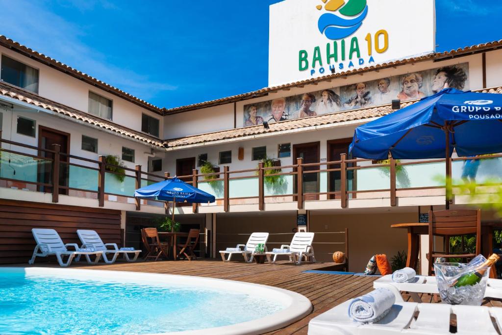 un hotel con piscina, sillas y sombrillas en Pousada Bahia 10, en Morro de São Paulo
