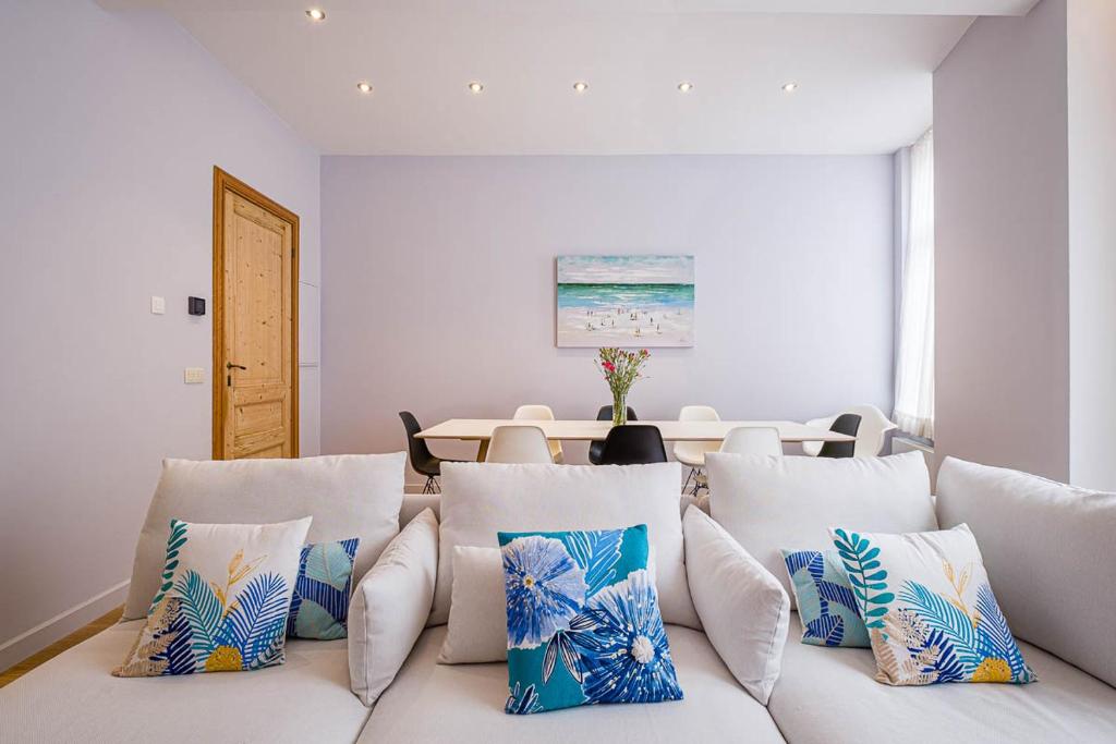 a living room with a white couch with pillows at Villa Louise Oostende in Ostend