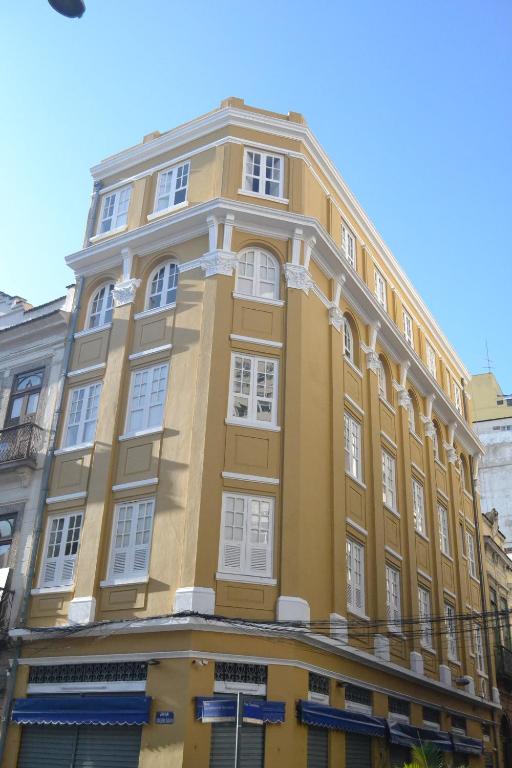 a yellow building with white windows on a street at Sangha Urbana - hostel, yoga & meditação in Rio de Janeiro
