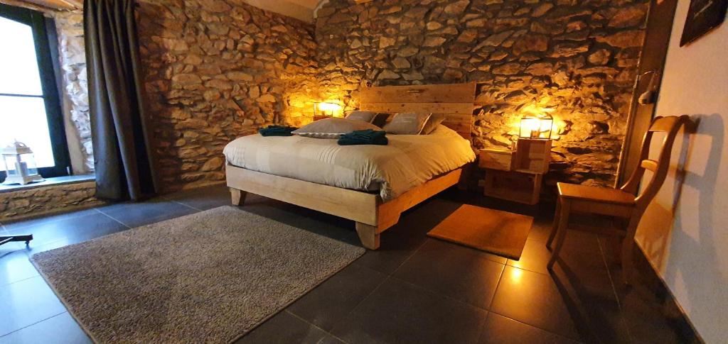 um quarto com uma cama e uma parede de pedra em O Près de la Lienne, maison de campagne de charme, accord parfait entre confort et authenticité em Lierneux