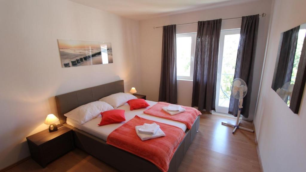 Apartments Stijak-Sorum في مالينسكا: غرفة نوم مع سرير مع وسادتين حمراء