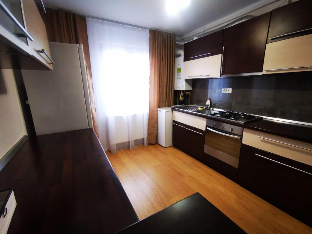 uma cozinha com armários pretos e piso em madeira em L&A apartments - Circumvalatiunii em Timisoara