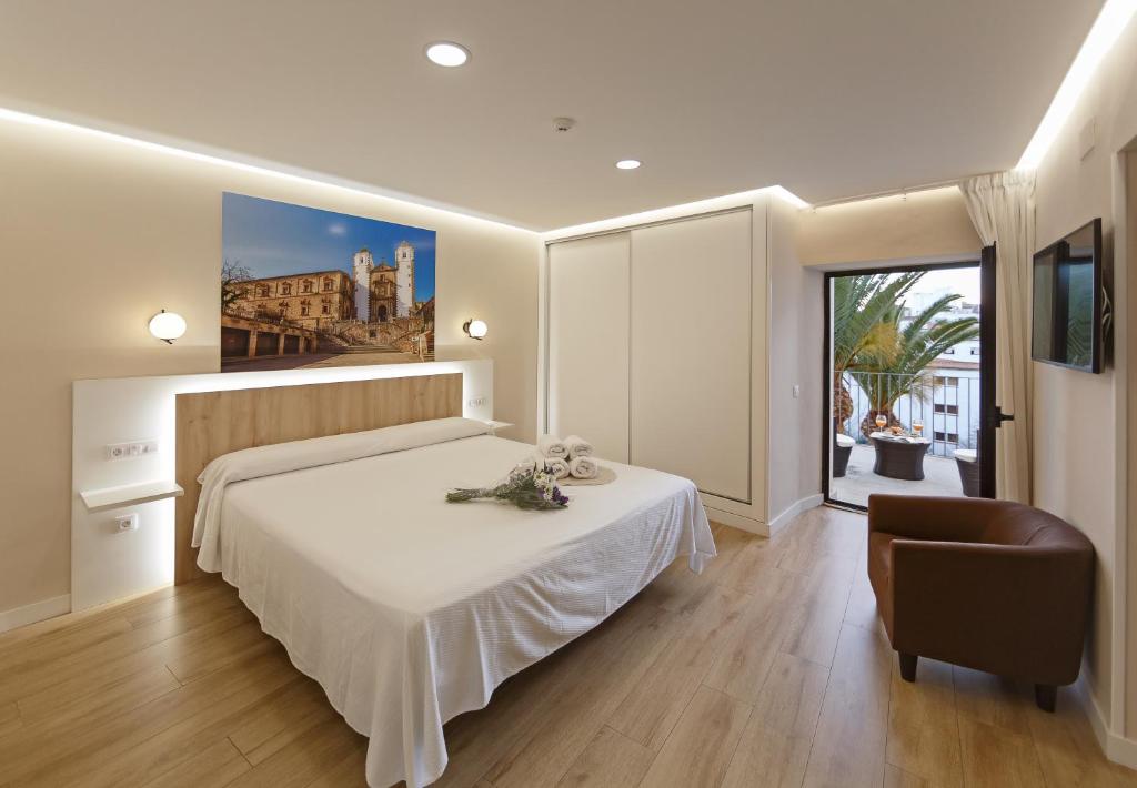 1 dormitorio con 1 cama blanca y 1 silla en Cáceres Deluxe, en Cáceres