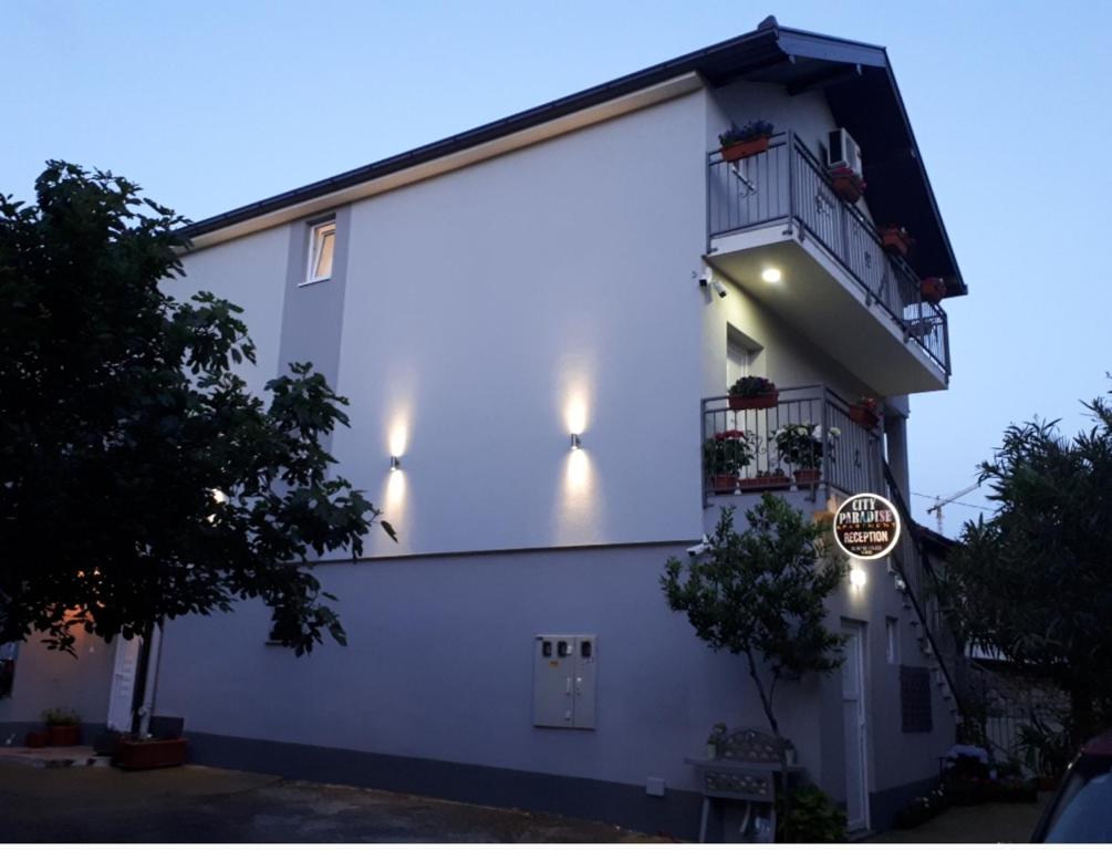 ein weißes Gebäude mit einem Balkon und einem Schild darauf in der Unterkunft Apartments City Paradise in Mostar