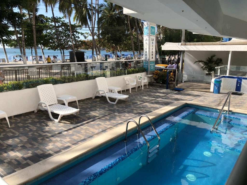 a swimming pool with chairs and a table and a beach at Hotel Be La Sierra in Santa Marta