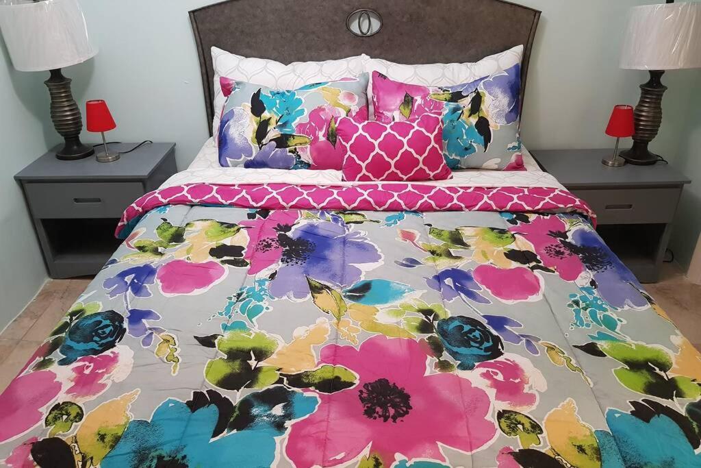 - un lit avec une couette et des oreillers colorés dans l'établissement The Cozy Corner, à Nassau
