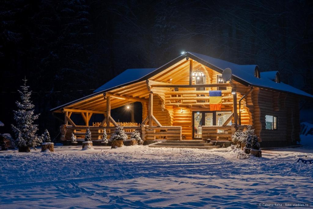 ein Blockhaus im Schnee in der Nacht in der Unterkunft Cabana Raisa in Valea Moldovei