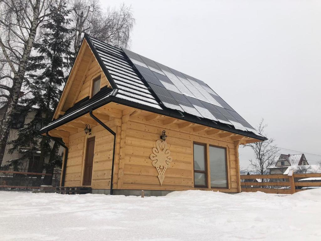 a cabin with a solar roof in the snow at Chatka u Górala in Jurgów