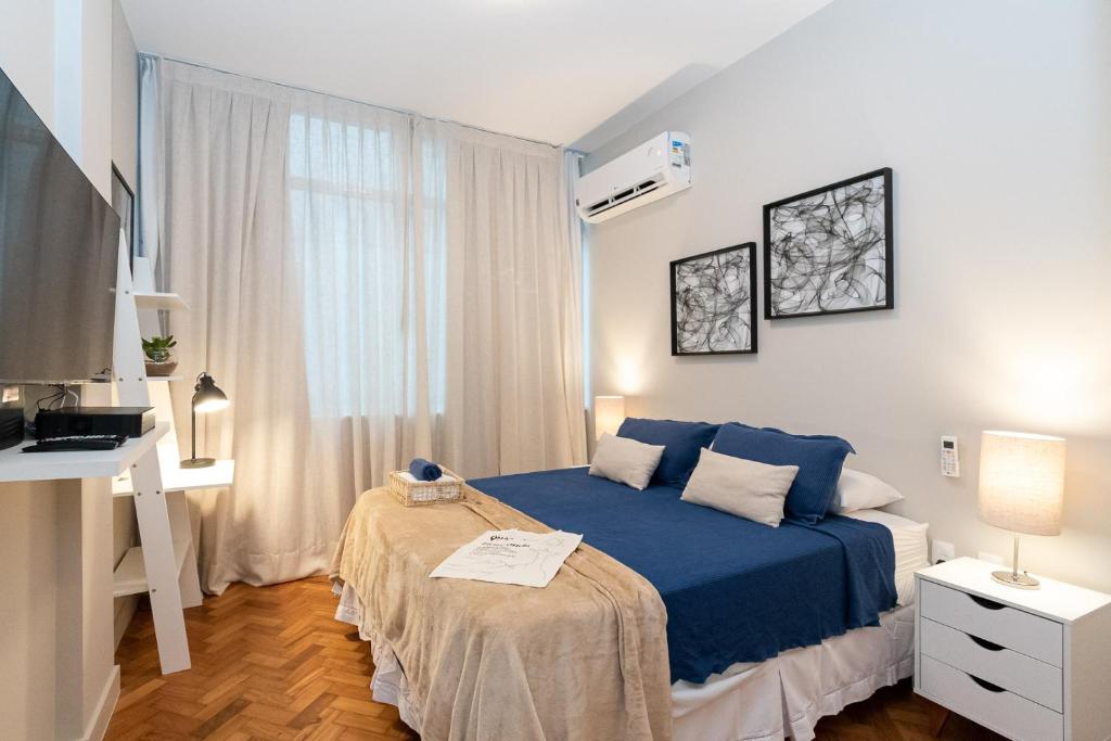 a bedroom with a blue bed and a desk at Studio a 200m da Praia de Ipanema | VP 463/308 in Rio de Janeiro