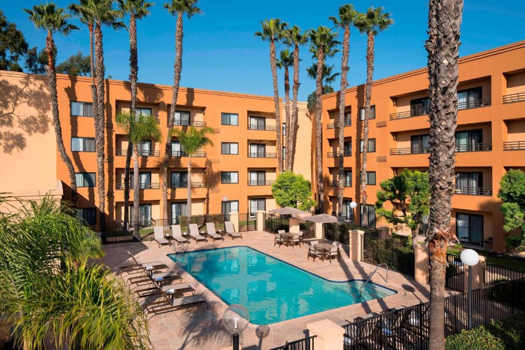 an exterior view of a hotel with a swimming pool and palm trees at Sonesta Select Los Angeles Torrance South Bay in Torrance