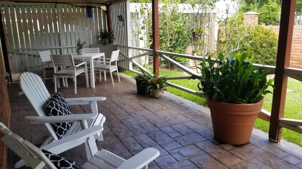 a patio with white chairs and a table and plants at Banya Bliss - Guest House in Bongaree