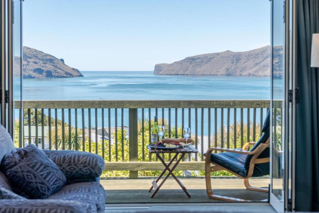 a room with a balcony with a view of the water at Seaview Outlook - Wainui Holiday Home in Wainui