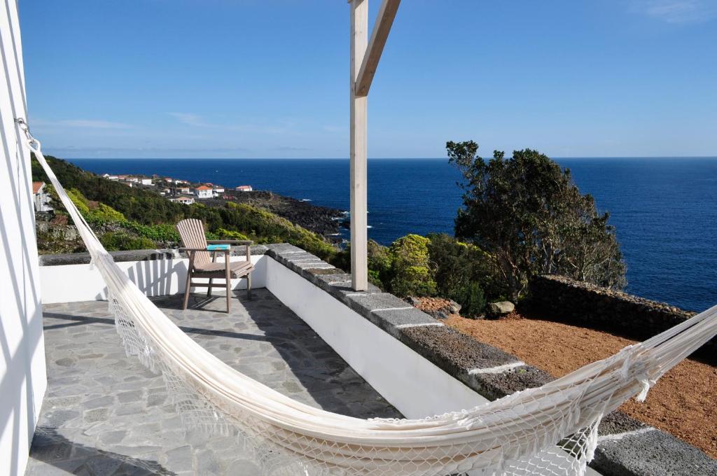 a hammock on the side of a house overlooking the ocean at Casa do Baleeiro in Calheta de Nesquim