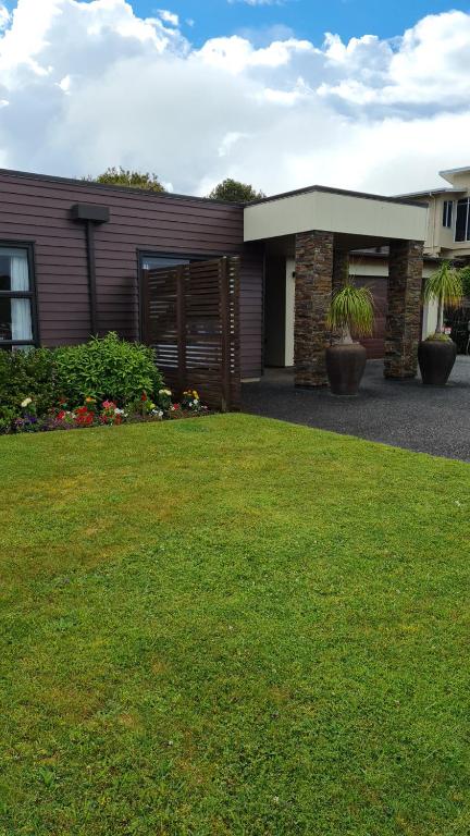 a house with a lawn in front of a building at Heta Road B&B in New Plymouth