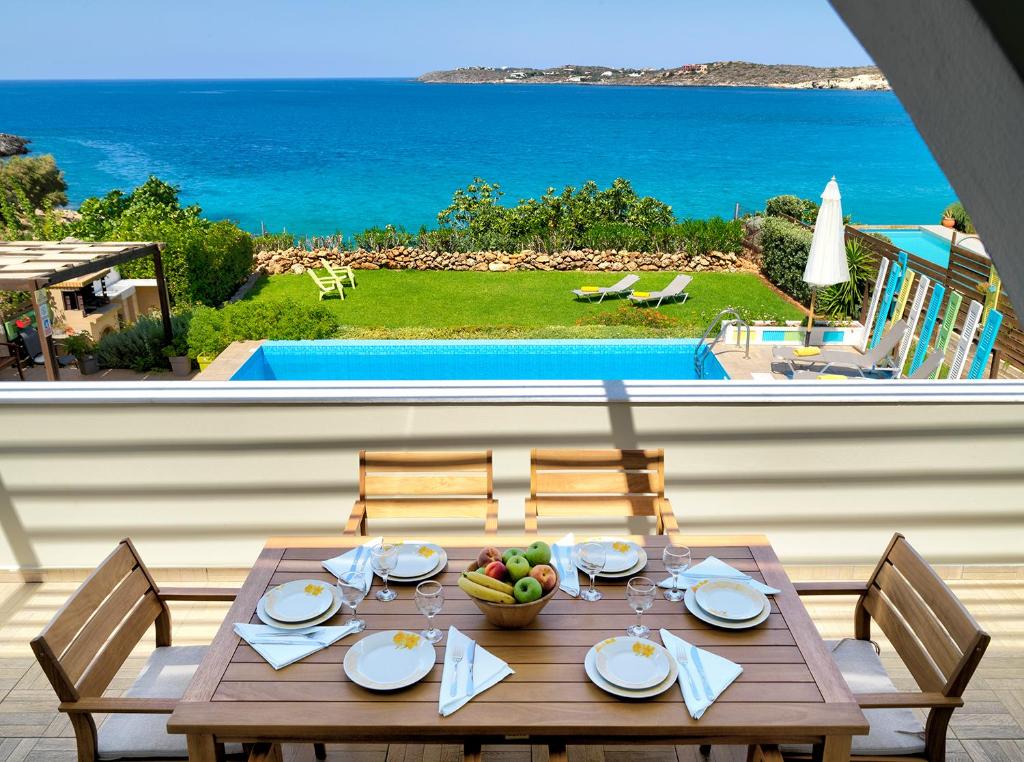 een houten tafel met een fruitschaal en uitzicht op de oceaan bij Villa Anemos by Estia in Kalathas