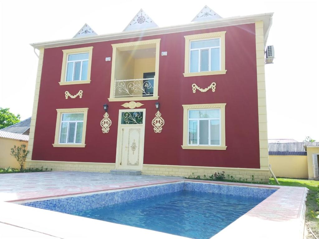 a red house with a swimming pool in front of it at Villa SUPER in Gabala