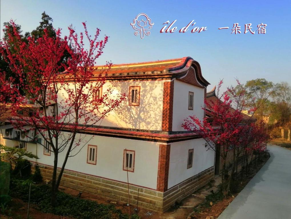 un bâtiment avec des arbres rouges devant lui dans l'établissement île d'or 一朵民宿 - 中蘭, à Jinsha