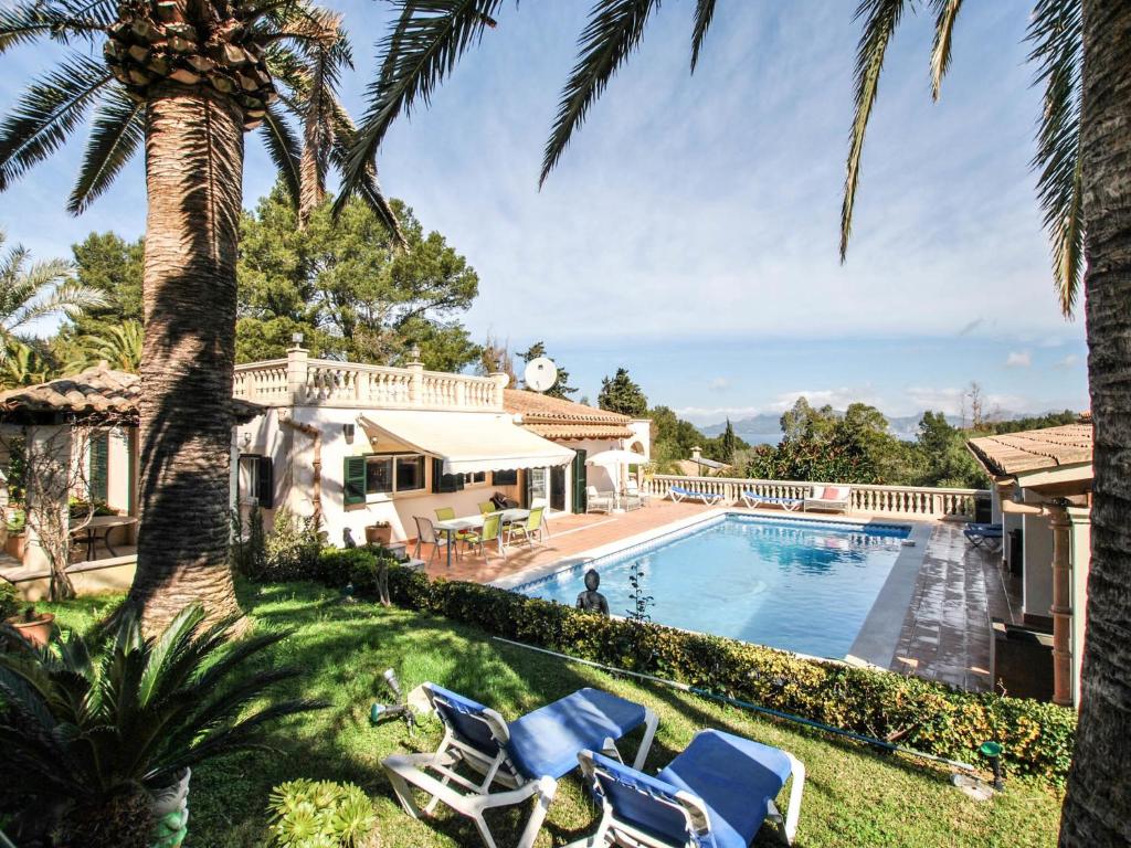 a villa with a swimming pool and palm trees at Belvilla by OYO Casa Aim Eri in Alcudia