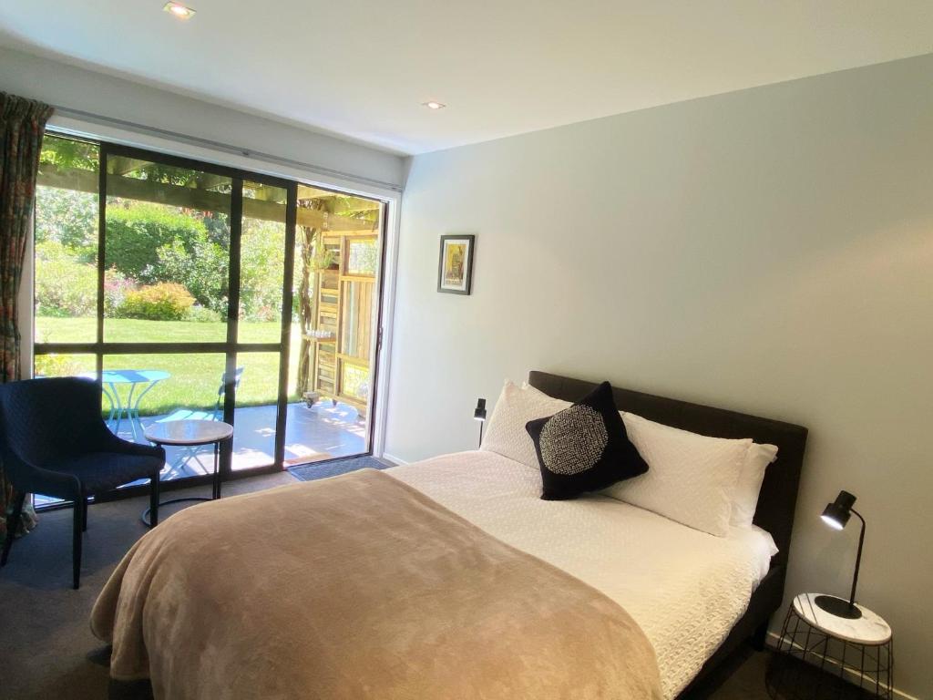 um quarto com uma cama e uma grande janela em The Garden Studio - Queenstown em Queenstown
