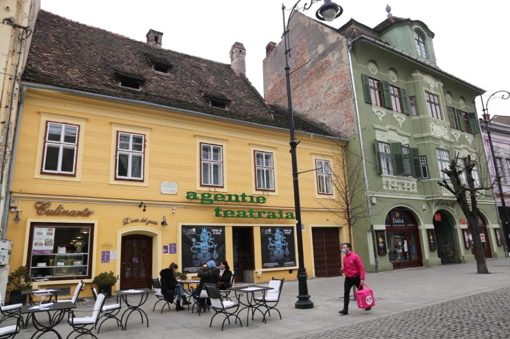 een vrouw die voor een geel gebouw loopt bij Balcescu Alina's apartament in Sibiu