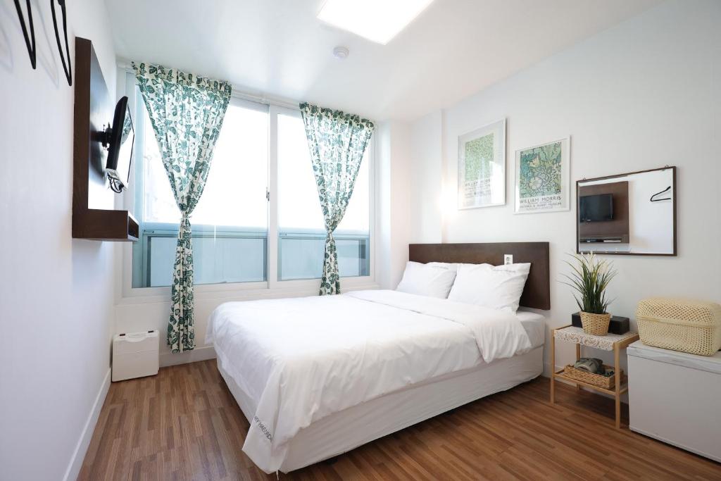 a white bedroom with a large bed and a window at Ekonomy Haeundae Hostel in Busan