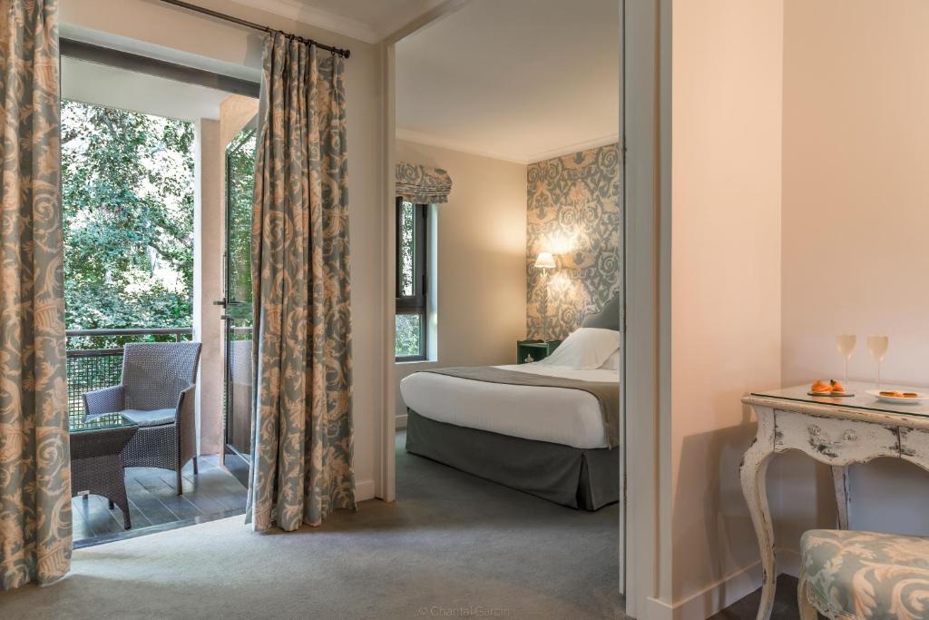 a hotel room with a bed and a balcony at Golf Hôtel de Valescure &amp; Spa NUXE in Saint-Raphaël