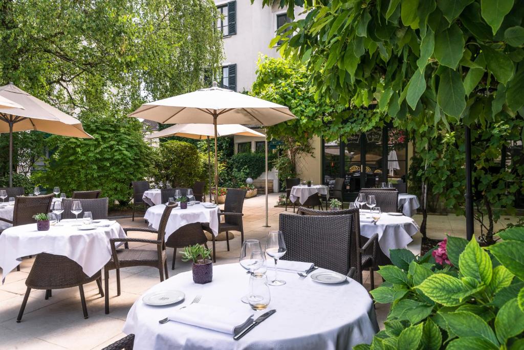 a restaurant with white tables and chairs and umbrellas at Hôtel de la Poste in Beaune