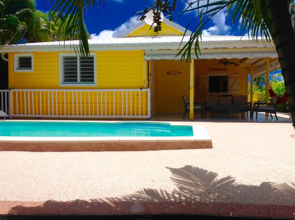 uma casa amarela com uma piscina em frente em La Villa Madinina em Les Trois-Îlets