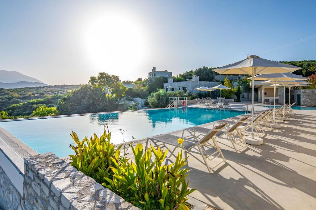 una gran piscina con sillas y sombrillas en Dalabelos Estate, en Angeliana