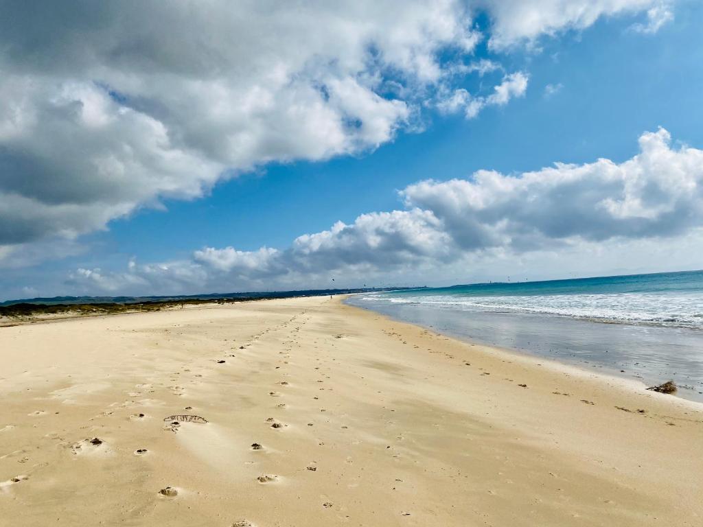 a beach with footprints in the sand and the ocean at Hotel Punta Sur in Tarifa