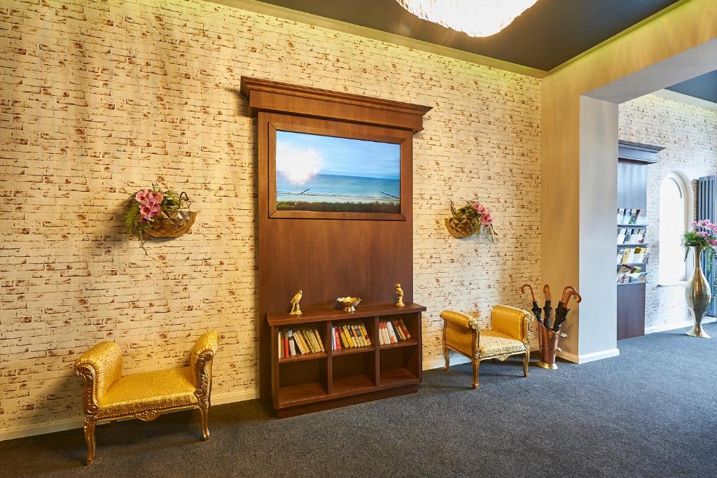 a waiting room with two chairs and a book shelf at Hotel Belvedere in Warnemünde
