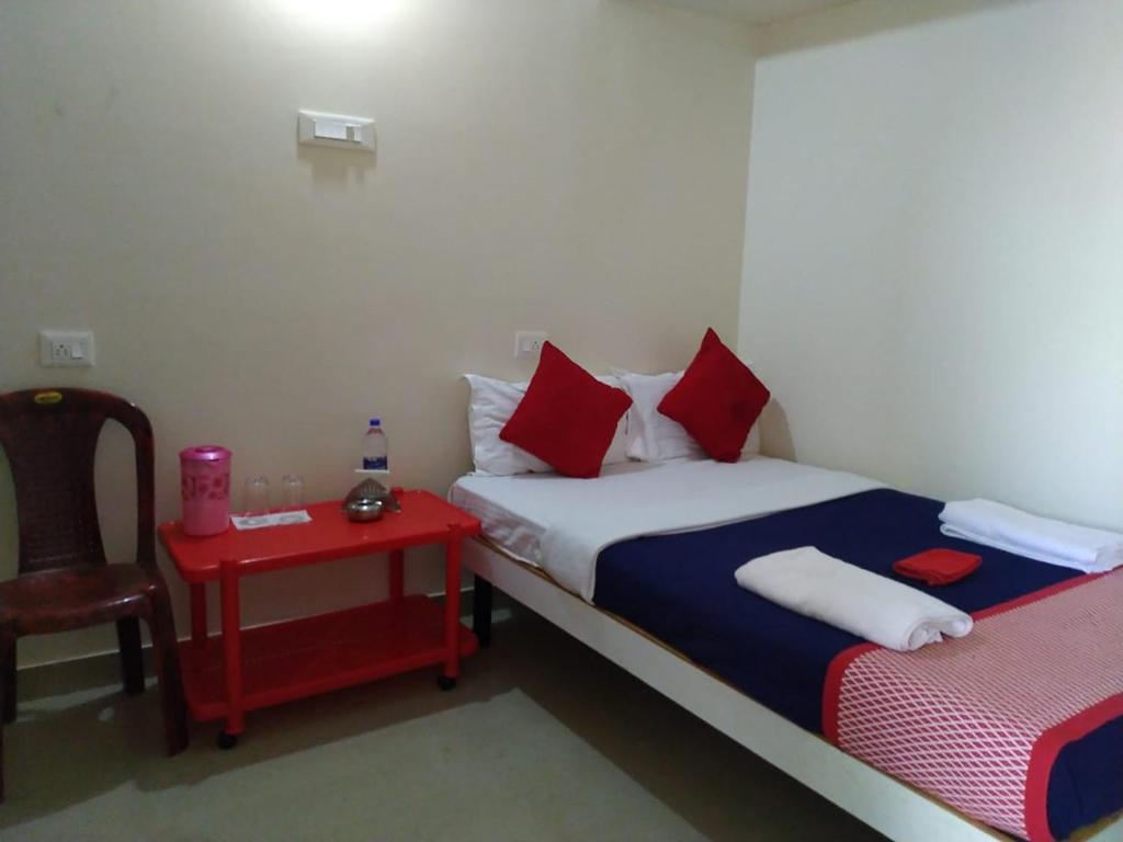 ein kleines Zimmer mit einem Bett und einem roten Tisch in der Unterkunft RAJE SAMBHAJI GUEST HOUSE in Belgaum