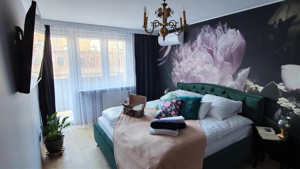 um quarto com uma cama com uma pintura de flores na parede em Mokotowska 67 by Homeprime em Varsóvia