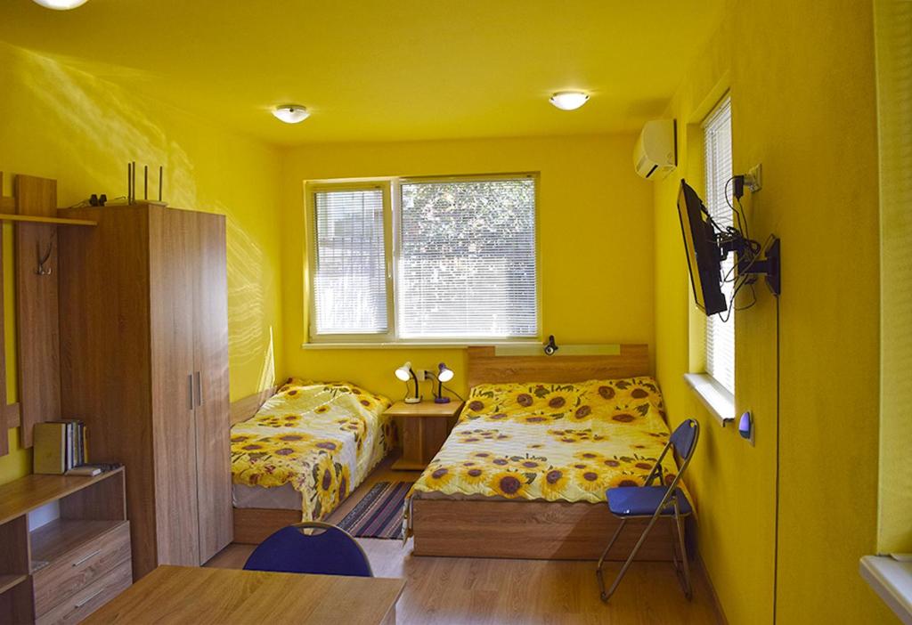 a yellow room with two beds and a window at Starlight Studios in Burgas City