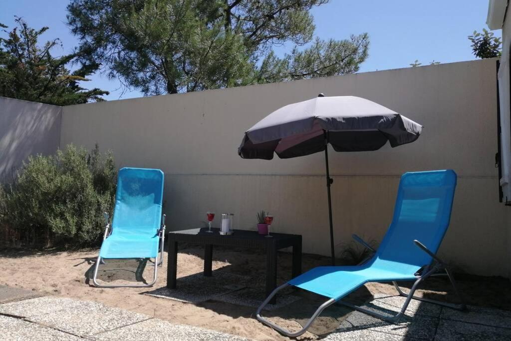 two blue chairs and a table with an umbrella at MAISON 3 CHAMBRES SUR UNE DUNE A 50 M DE LA PLAGE in La Tranche-sur-Mer