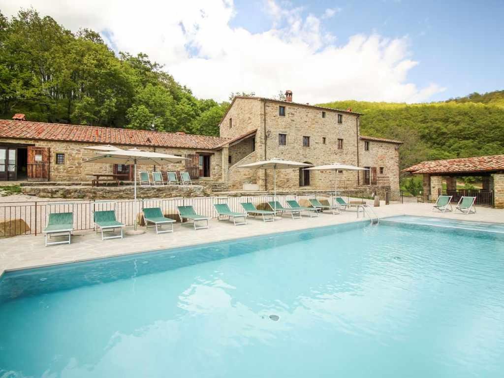 een groot zwembad met stoelen en een gebouw bij Villa Santarsa con piscina privata in Sansepolcro