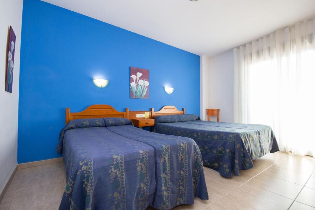 2 camas en una habitación con una pared azul en Hotel Rosi, en Benicarló