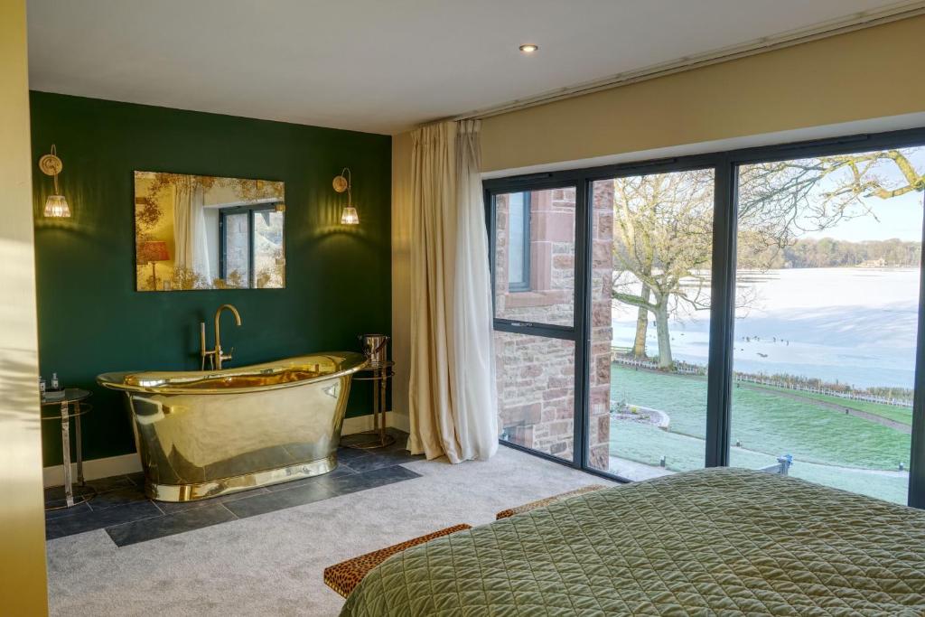 a bedroom with a tub and a large window at Tarn End Cottage 8, Talkin Tarn, Brampton in Carlisle