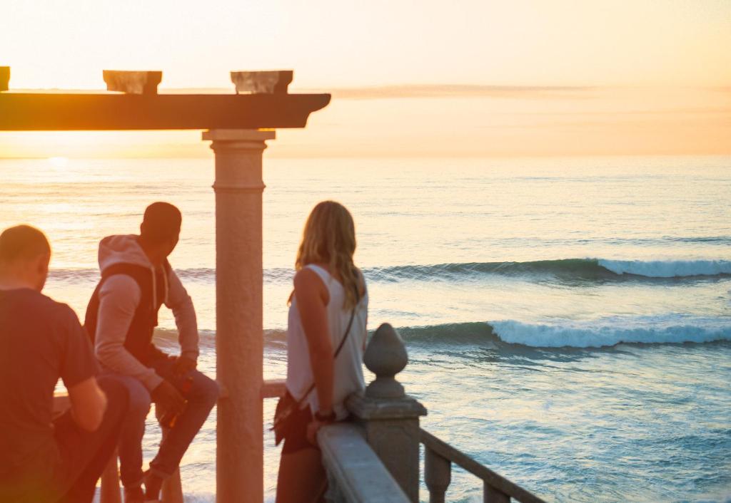 Un groupe de personnes assises sur une jetée donnant sur l'océan dans l'établissement Laneez Ericeira Surf House, à Ericeira