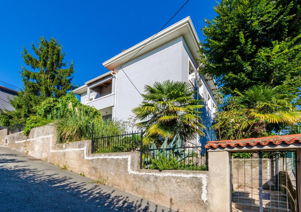 a white house with a fence and trees at Apartments Andrijana in Rijeka
