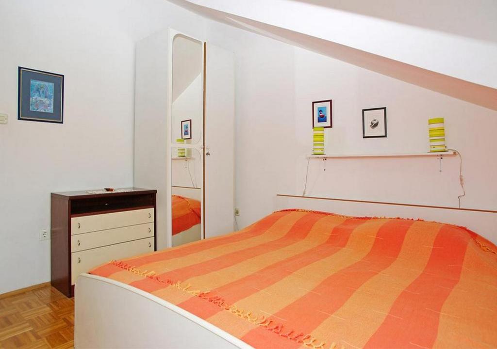 a bedroom with a bed and a dresser and a mirror at Apartments Tomašić in Smokvica