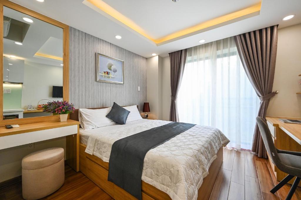 a bedroom with a bed and a desk and a mirror at Nikko Hotel - The Classy Life in Ho Chi Minh City